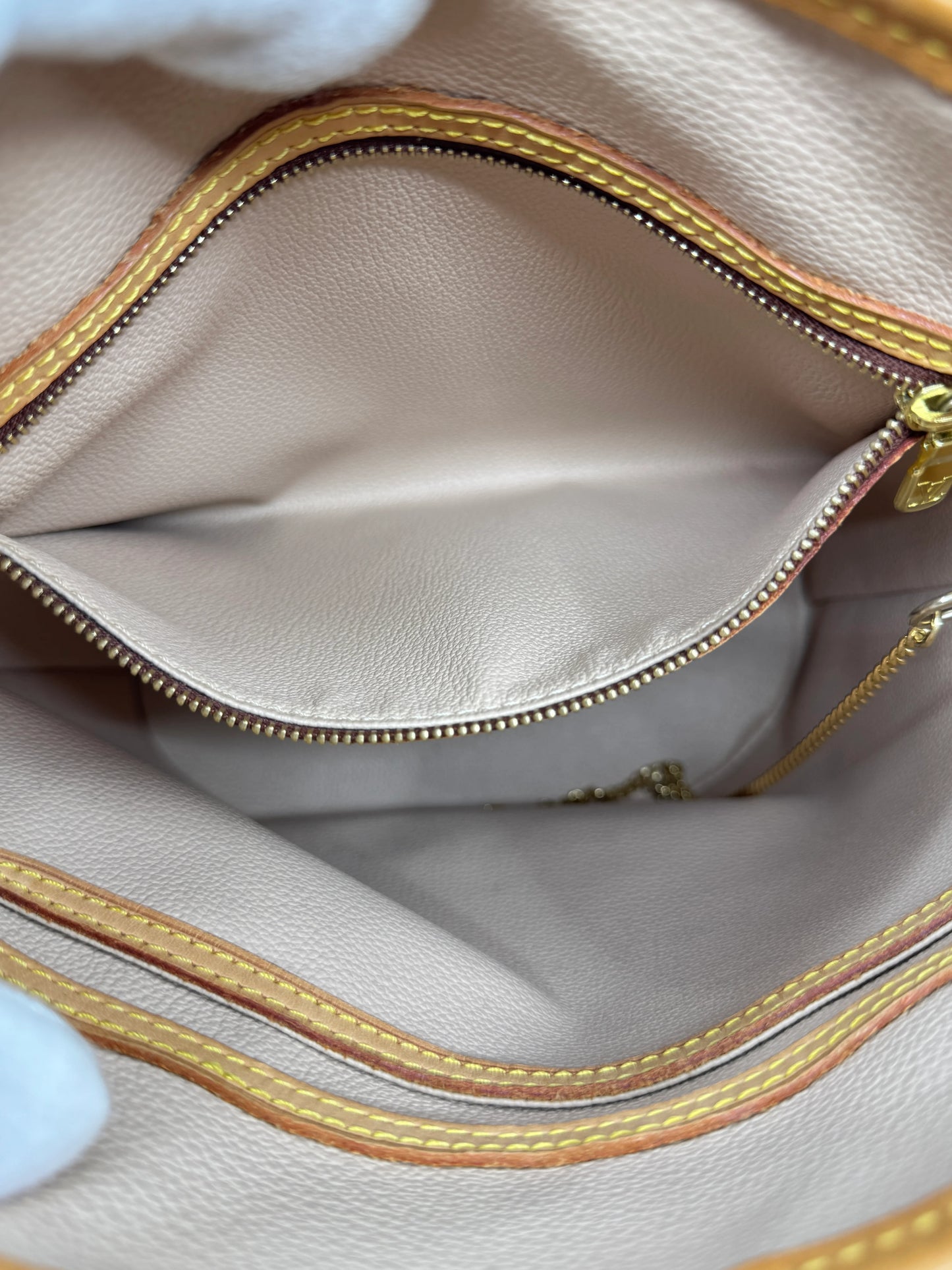 interior-of-louis-vuitton-monogram-petit-bucket-bag-compartment-with-golden-zipper-closure-and-vachetta-leather-border-details